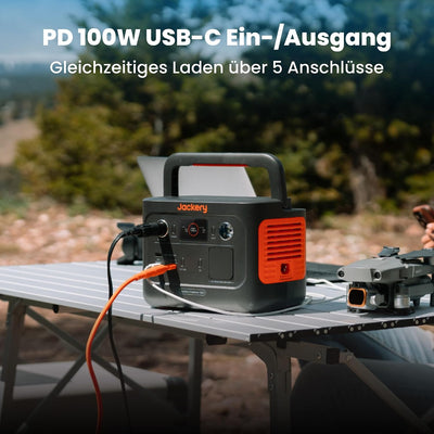 Jackery Explorer 240 v2 auf dem Campingtisch lädt mehrere Geräte gleichzeitig über USB-C mit 100 W